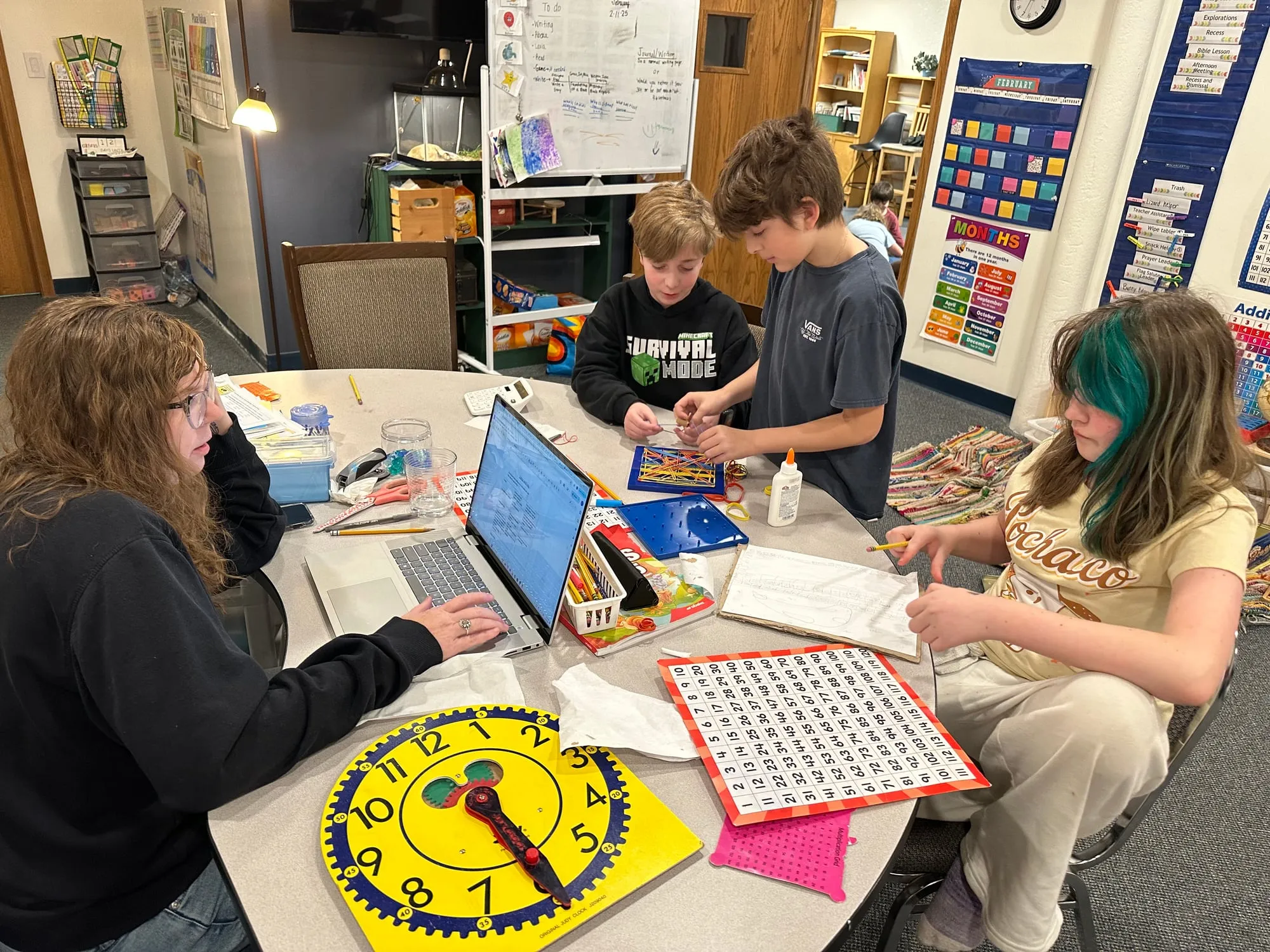 A teacher working with a small group of students around a table